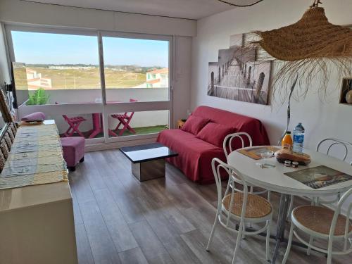 a living room with a red couch and a table at RIEZ Entre Mer et Dunes in Saint-Hilaire-de-Riez