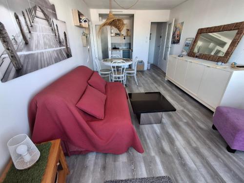 a living room with a red couch and a kitchen at RIEZ Entre Mer et Dunes in Saint-Hilaire-de-Riez