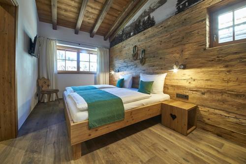 a bedroom with a bed with a wooden wall at Panorama Chalets by we rent, JOKERCARD INCLUDED in Saalbach-Hinterglemm