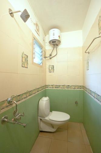 a bathroom with a toilet in a green bathroom at Blessings select DLF in Chennai