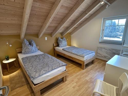 two beds in a room with wooden ceilings at Brückelsee-Chalet in Wackersdorf