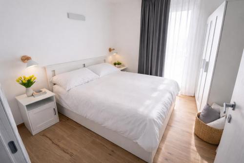 a white bedroom with a white bed and a window at Bormio7 con parcheggio, pista ciclabile, vicino piste sci e terme in Valdisotto