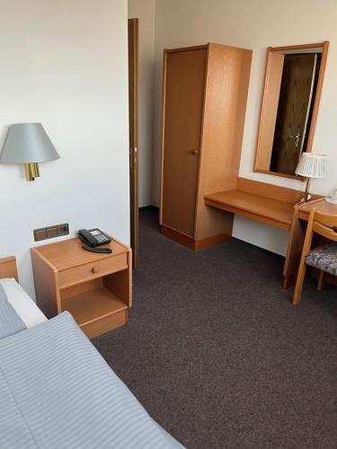 a hotel room with a bed and a desk and a mirror at Hotel Landhaus Adensen in Nordstemmen