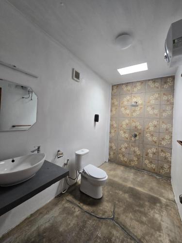 a bathroom with a white toilet and a sink at Villa Lamorna in Krui