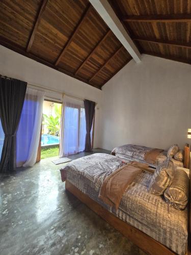 a bedroom with a bed and a large window at Villa Lamorna in Krui