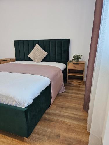 a bedroom with a bed with a green headboard at At Ladyluck in Suceava