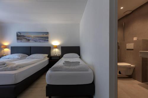 two twin beds in a room with a bathroom at Hotel Randenbroek in Amersfoort
