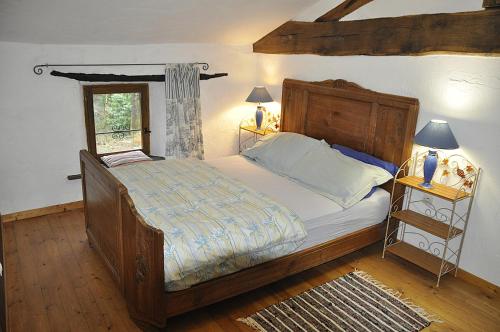 a bedroom with a large bed with a wooden frame at Les Glycines Gîtes - Les Petites Pierres gîte - shared solar heated pool - garden spa - small dogs welcome in Vernoux-en-Gâtine