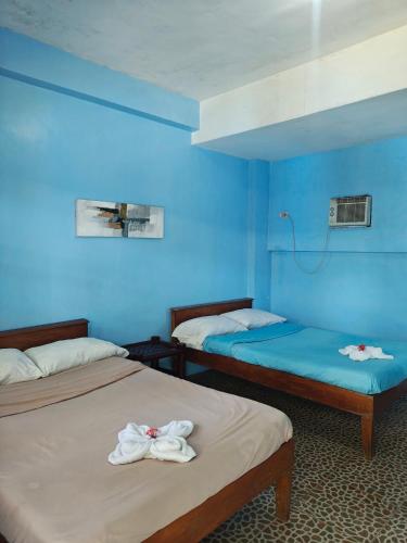 two beds in a room with blue walls at Satosa Beach Resort in San Joaquin