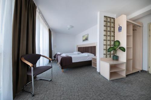 a bedroom with a bed and a chair in a room at Hotel Logos in Warsaw