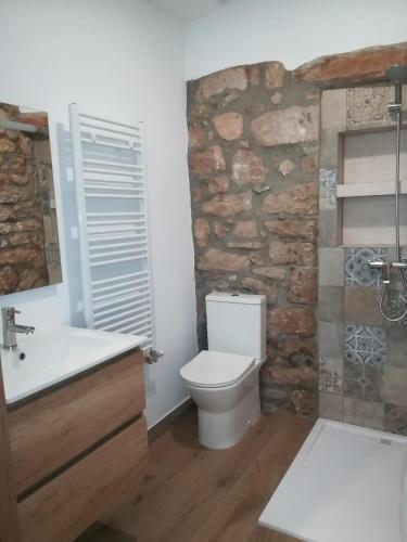 a bathroom with a stone wall and a toilet and sink at Mas Lloretó - El Rossinyol in Copóns