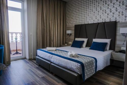 a bedroom with a large bed with blue pillows at Hotel Fiesa in Piran