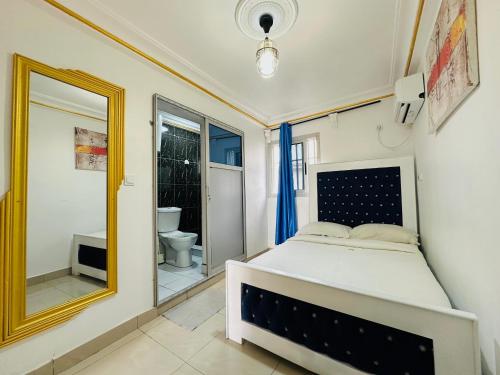 a bedroom with a bed and a mirror at CAMERHOME Banque SCB Cité des palmiers in Douala