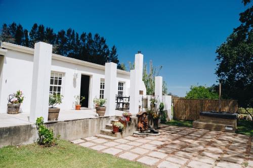 a white house with a fence and a patio at The Hamlet in Swellendam