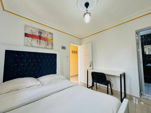 a bedroom with a white bed and a desk at CAMERHOME Banque SCB Cité des palmiers in Douala