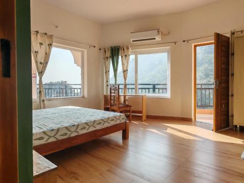 a bedroom with a bed and two large windows at Om Homestay in Rishīkesh