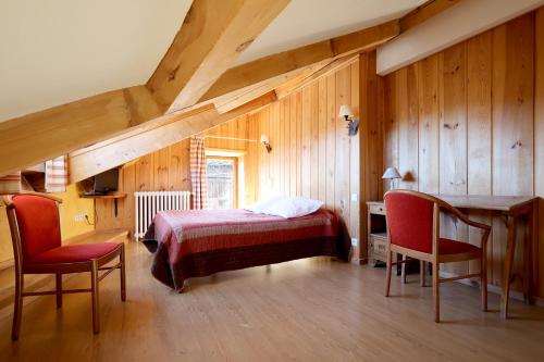 a bedroom with a bed and a desk and chairs at Hôtel Picheyre in Formiguères