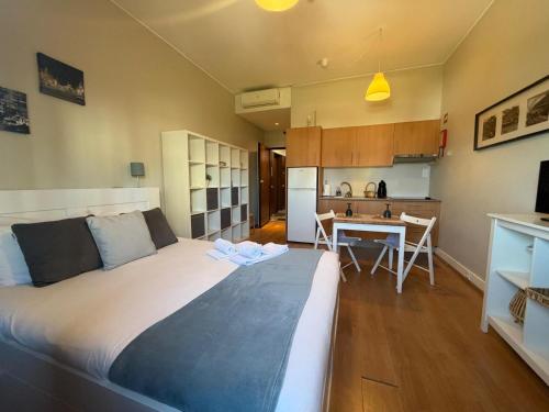 a bedroom with a large bed and a kitchen at Oporto Trindade Residence in Porto