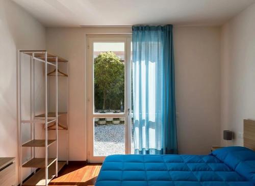 a bedroom with a blue bed and a glass door at Bellagio Wave Apartment in Bellagio