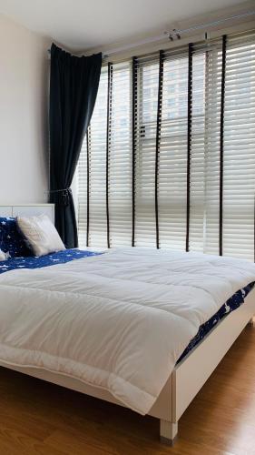a large bed in a bedroom with windows at สุขุมวิท101 By KT in Amphoe Phra Khanong