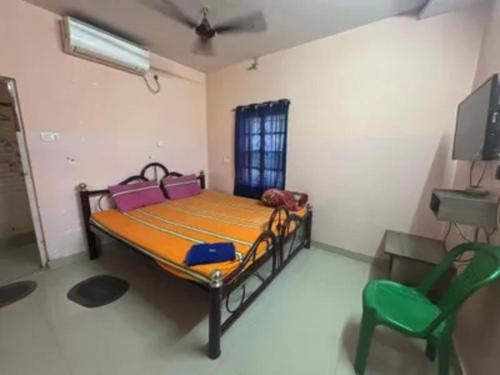 a bedroom with a bed and a green chair at Via Ashiyana Inn in Kolkata