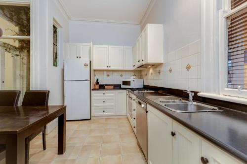 a kitchen with white cabinets and a white refrigerator at Seymours On Lydiard in Ballarat