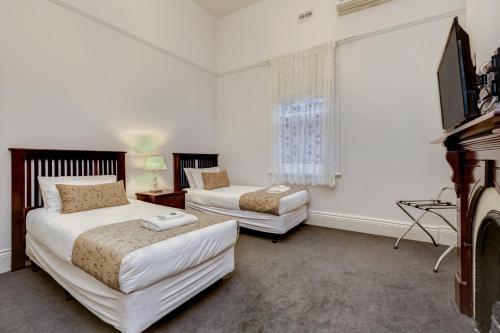 a bedroom with two beds and a television in it at Seymours On Lydiard in Ballarat