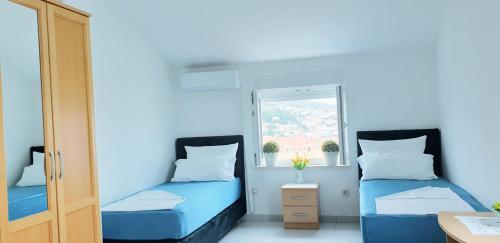 two beds in a small room with a window at Apartments Slavica Trogir in Trogir