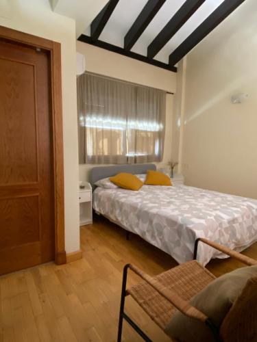 a bedroom with two beds and a window and a chair at El rincón de Bonilla in El Ronquillo