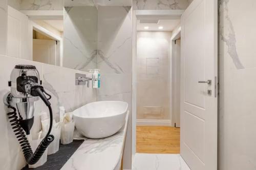 a white bathroom with a hair dryer on a counter at The Place 217 in Rome