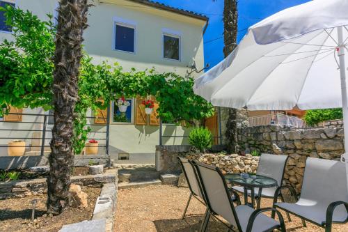 a table and chairs with an umbrella in front of a house at House Tinac in Crikvenica