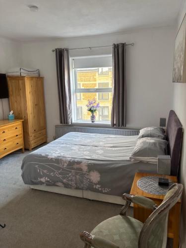 a bedroom with a bed and a window and a chair at Crispin House in Hunstanton