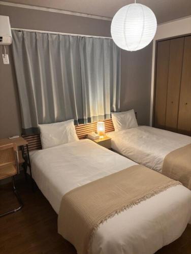 two beds in a hotel room with a window at Matsudo in Matsudo