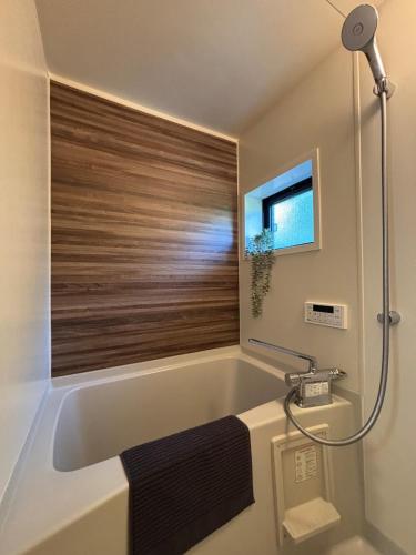 a bathroom with a bath tub with a window at Matsudo in Matsudo