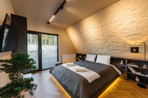 ein Schlafzimmer mit einem Bett und einer Steinwand in der Unterkunft Sunset A Frames in Bălceşti