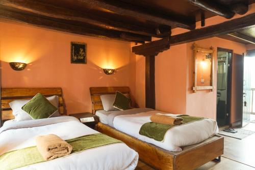 two beds in a room with orange walls at Bandipur Bazar Ghar in Bandipur
