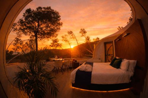a bed in a tent with a sunset in the background at Glamping Balú in Monesterio