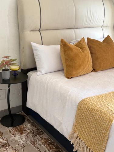 a white bed with yellow pillows and a side table at The golf estate gateway in Roodepoort