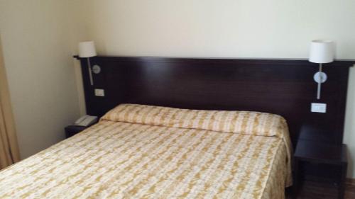 ein Schlafzimmer mit einem Bett mit hölzernem Kopfteil in der Unterkunft Hotel Due Colonne in Cagliari