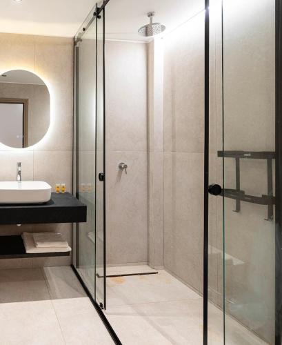 a bathroom with a glass shower and a sink at Elysian Studio A4 in Karpathos