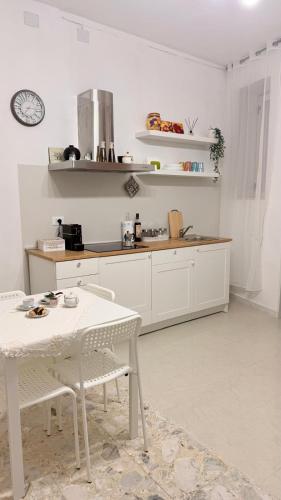a white kitchen with a table and a counter at Lucy Home in Pisticci