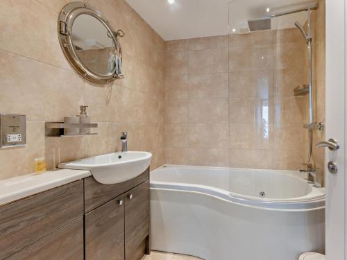 a bathroom with a tub and a sink and a mirror at 2 Bed in Bideford oc-65074 in Northam