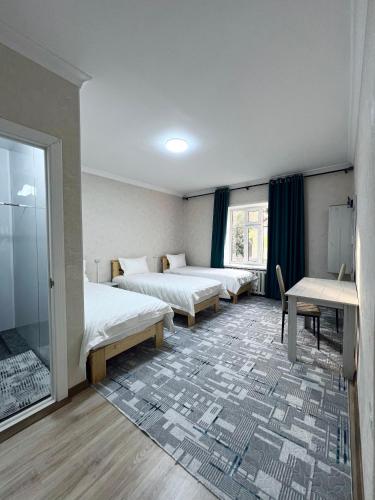 a room with two beds and a table and a window at Tabylga guest house in Jalal-Abad
