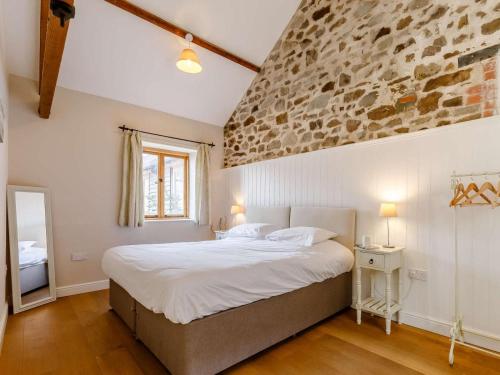 a bedroom with a large bed with a stone wall at 2 Bed in Umberleigh oc-09091 in Umberleigh Bridge