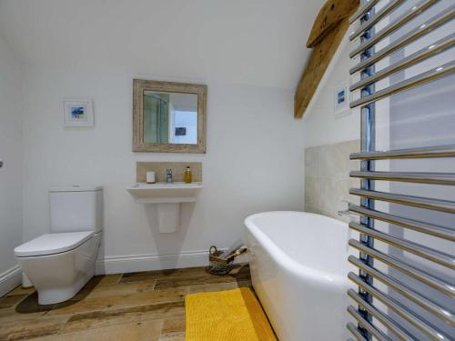 a bathroom with a tub and a toilet and a sink at 4 Bed in Honiton oc-45563 in Payhembury