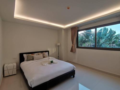 a bedroom with a large bed and a window at คลับรอยัล2bed in North Pattaya