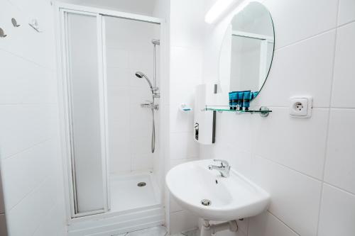 a white bathroom with a sink and a shower at Little Mountain Apartment in Ostružná