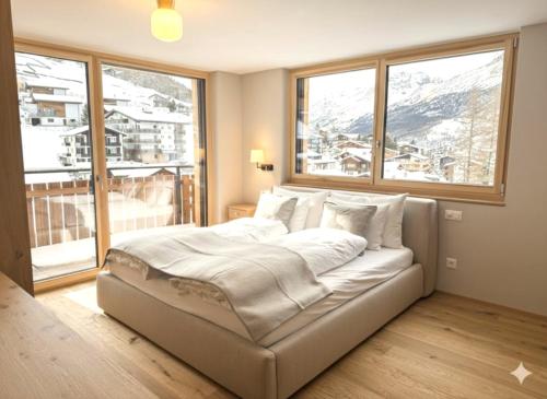 a large bed in a room with a large window at Alphubel PEAK in Saas-Fee
