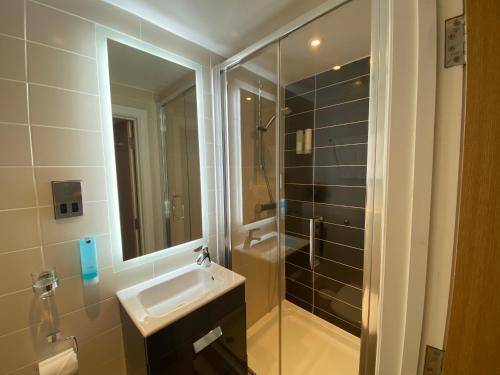 a bathroom with a sink and a shower with a mirror at The Suites - St Pancras Hotel Group in London