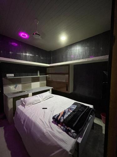 a bedroom with a large bed with purple lights at HOTEL Welcome in Jāmb